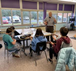 Sam Colegrove teaching a group of four students how to play the ukulele. 